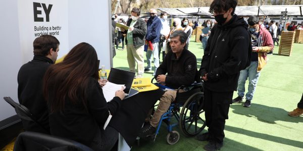 Persona en silla de ruedas inscribiéndose en una feria laboral.